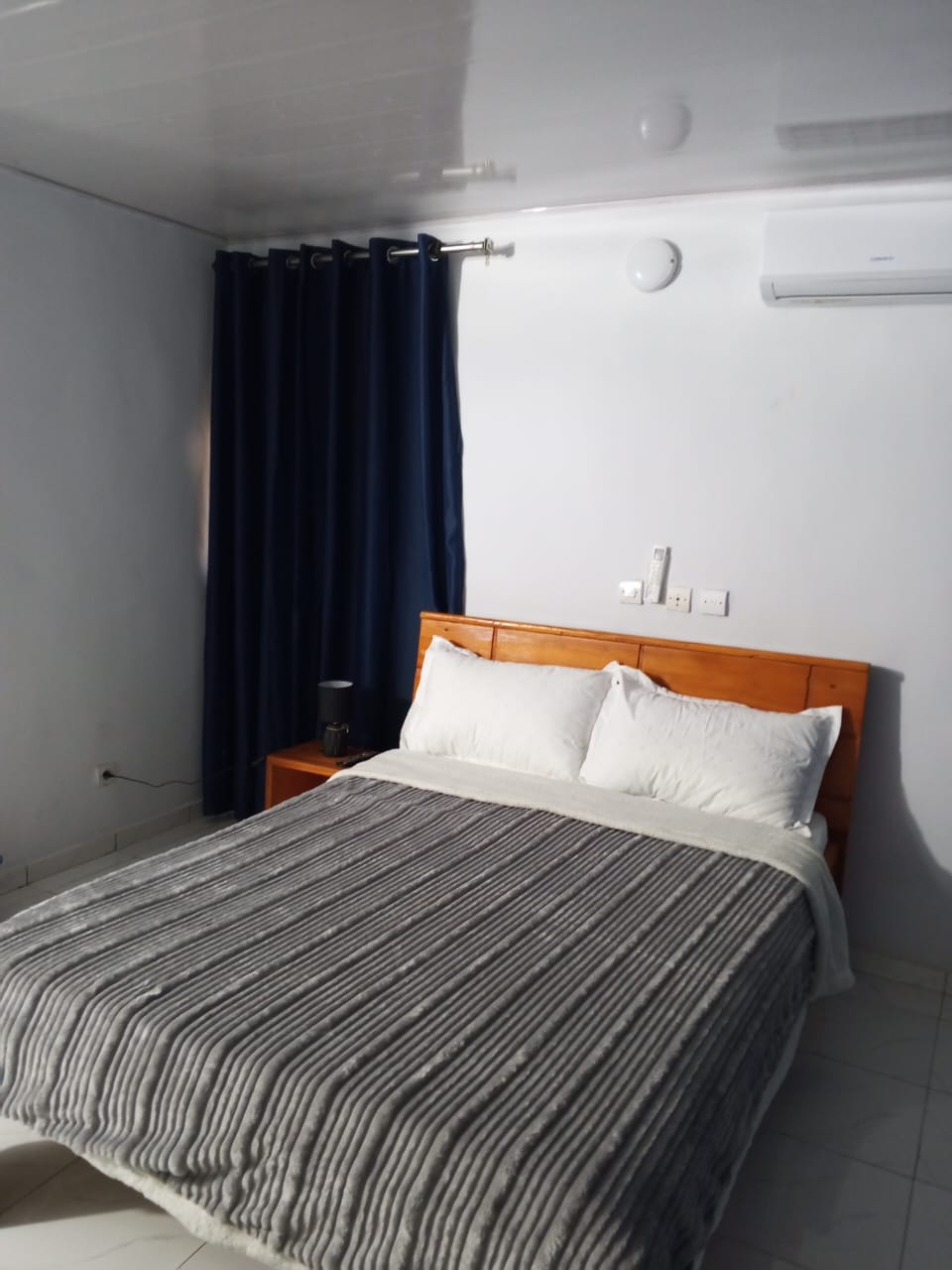 Chambre avec rideaux bleu marine, lit double et couette grise rayée