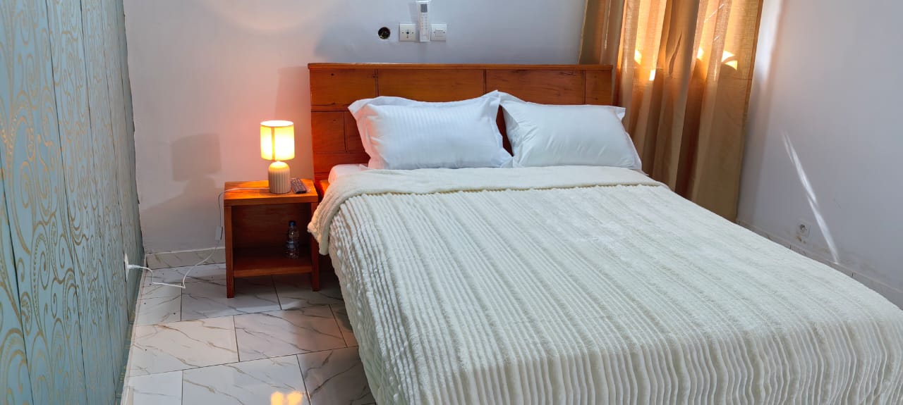 Chambre confort — lit double, tête de lit en bois, lampe de chevet