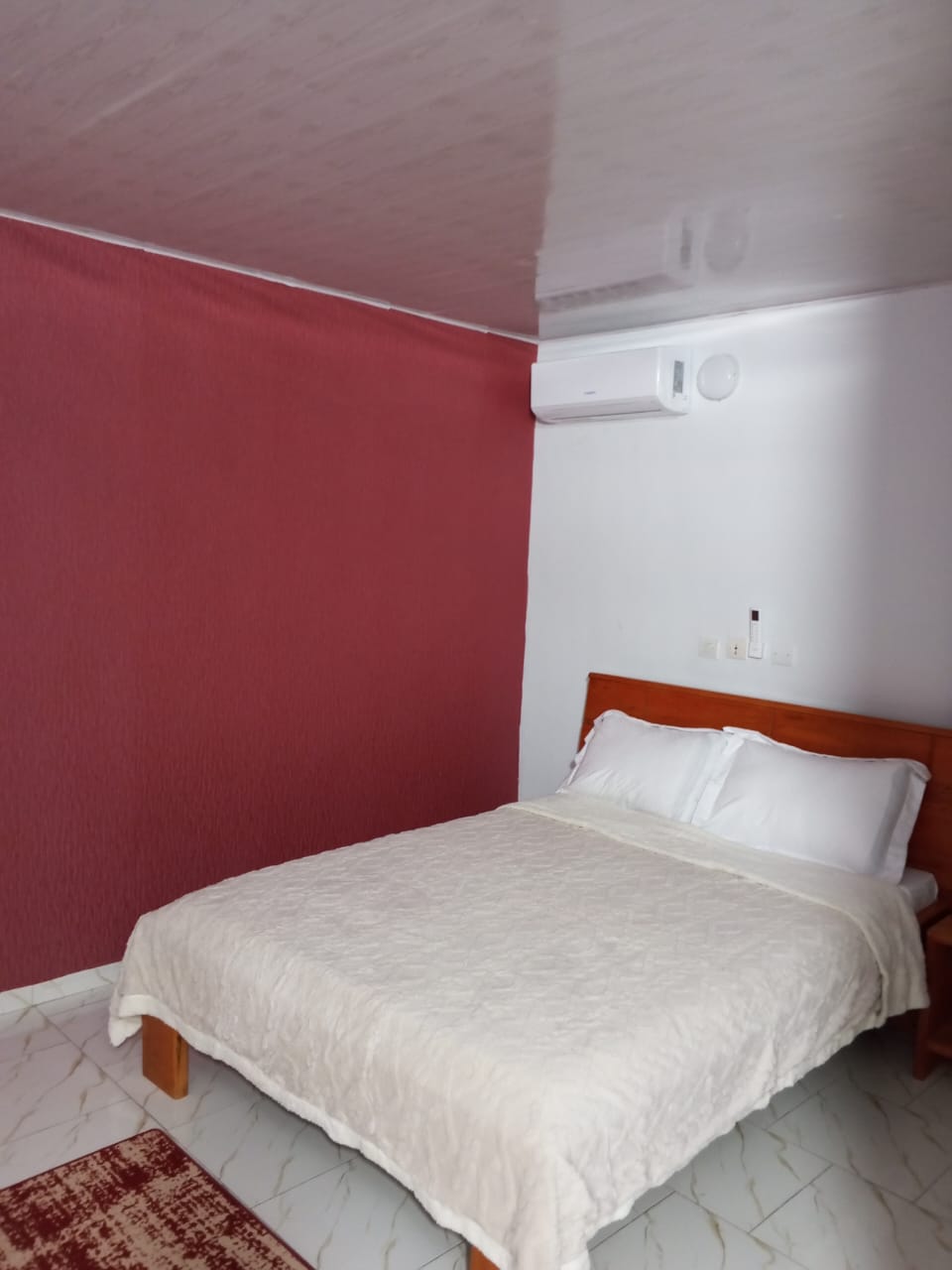 Chambre avec mur rouge sobre et couette blanche immaculée