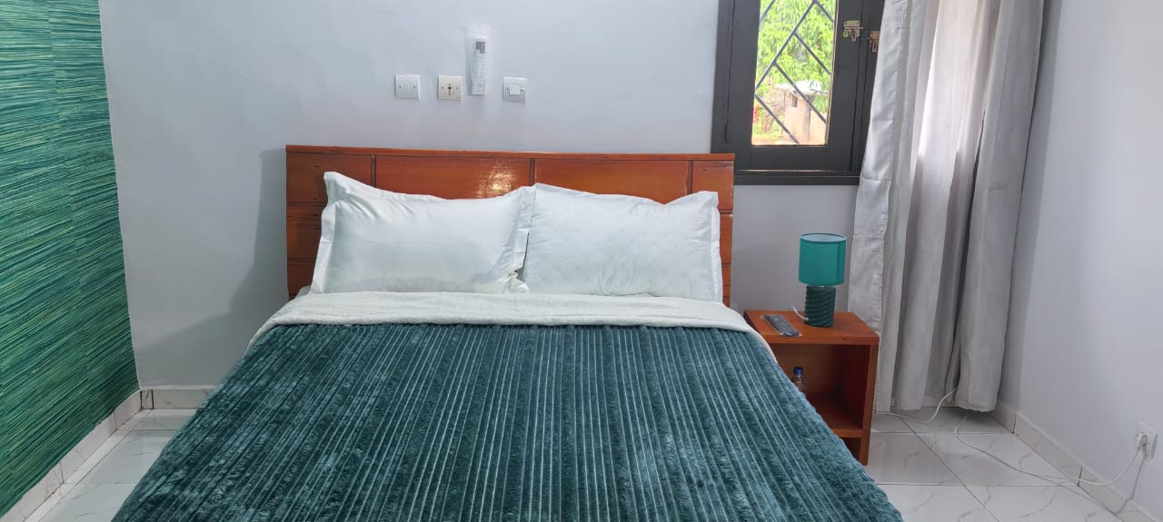 Chambre avec mur vert teal, lit double et fenêtre sur le jardin