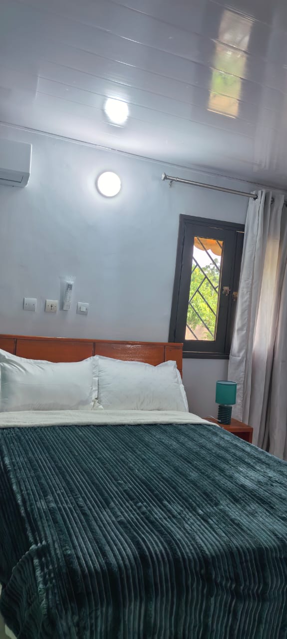 Chambre avec couette vert foncé et fenêtre lumineuse sur le jardin